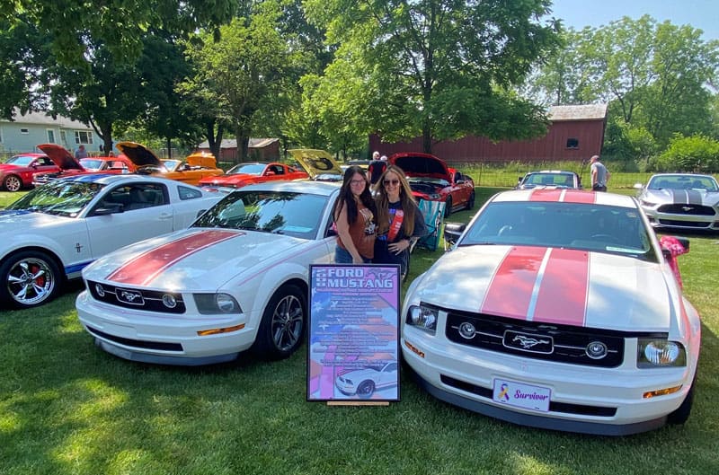 2 girls with their white and red mustangs