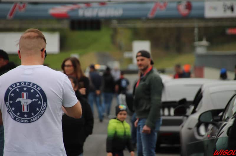 Man in EMCA shirt in front of cars and crowd