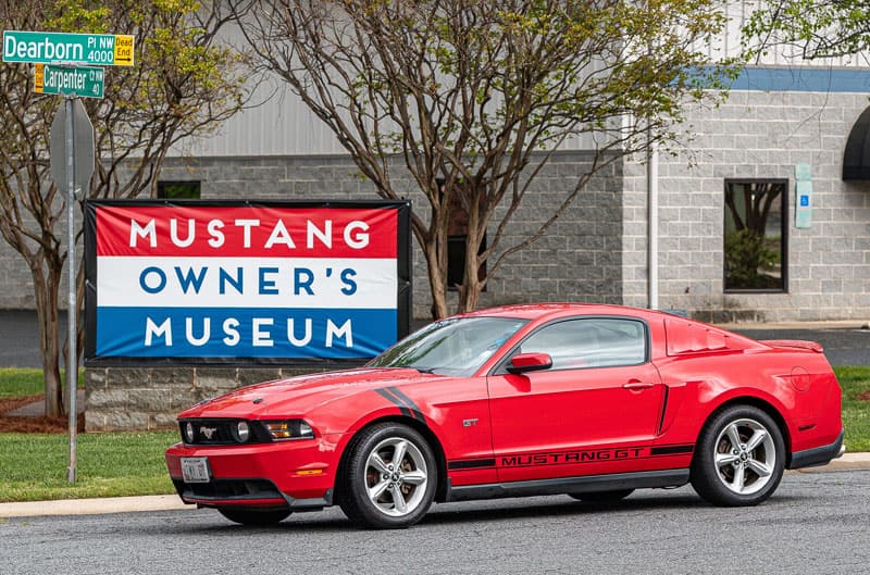 Red Mustang in front of sign
