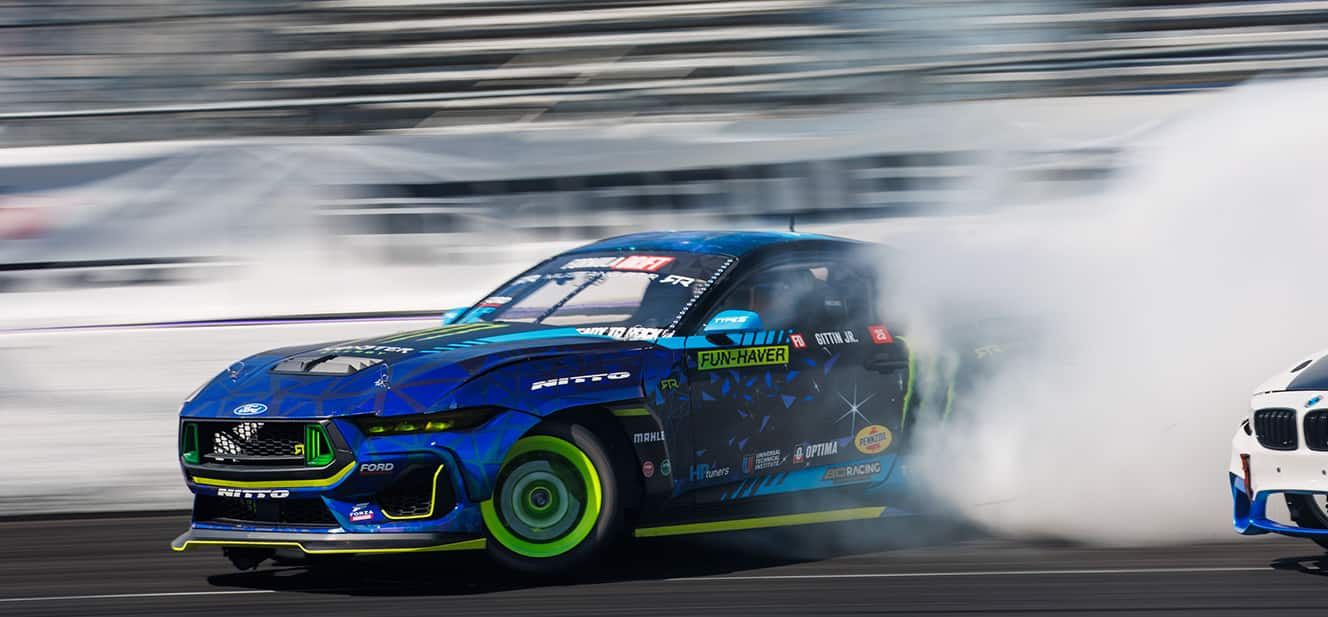 Vaughn Gittin's blue and green number 25 Ford mustang race car on track