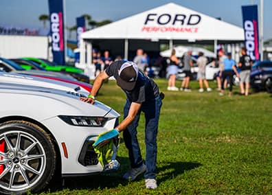 Person wiping down their white Mustang at a club event