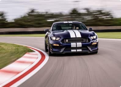 A blue Ford Mustang navigating a curve.