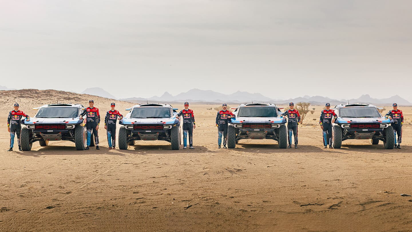 Dakar rally team photo with members standing next to cars