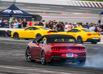 A red Ford Mustang driving at an Enthusiast event.