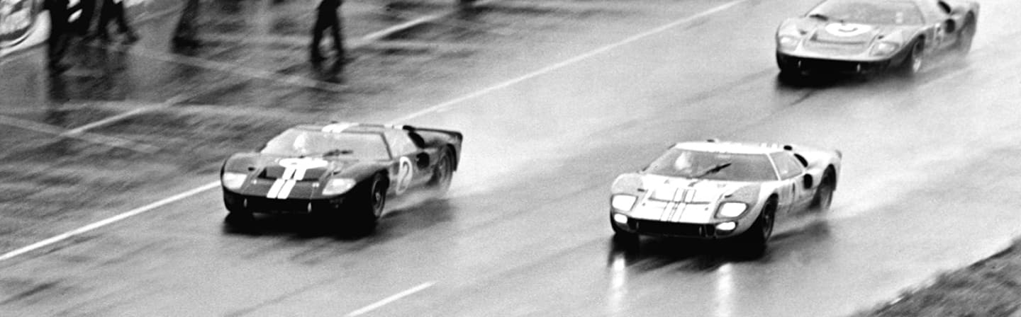 Archival image of race cars in motion on racetrack	