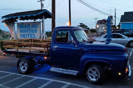 Side profile of Norm's 1955 F-100 Stakeside Platform Flatbed parked at a motel