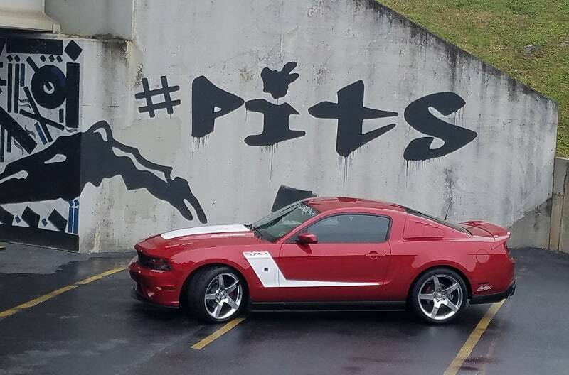 Side profile of 2015 Ruby Red 50th Anniversary Edition Mustang GT parked in front of graffiti