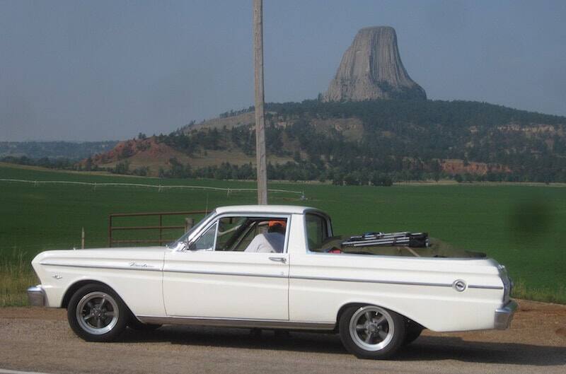 Side view of white 1965 Ford Falcon Ranchero parked in front of mountain scenery