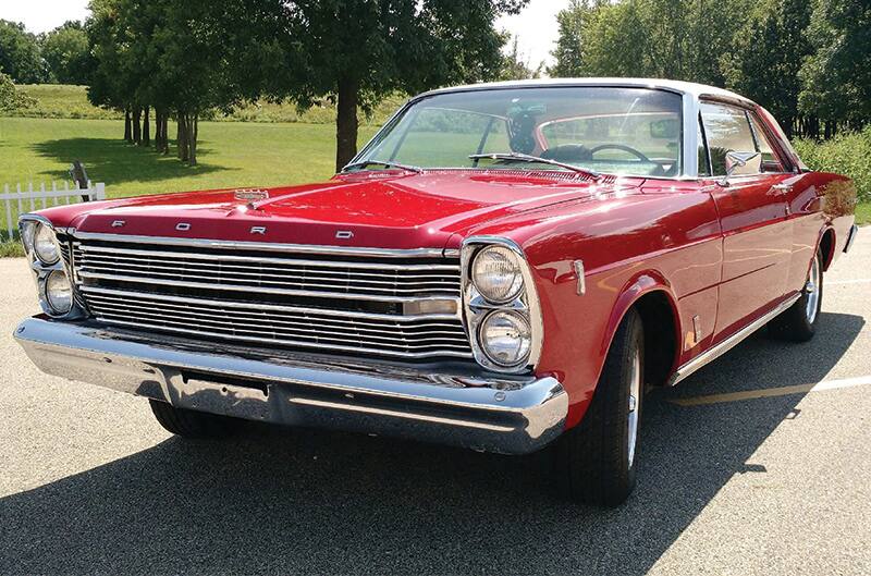 Front profile of red 1966 Ford Galaxie 500 parked with trees and grass in background