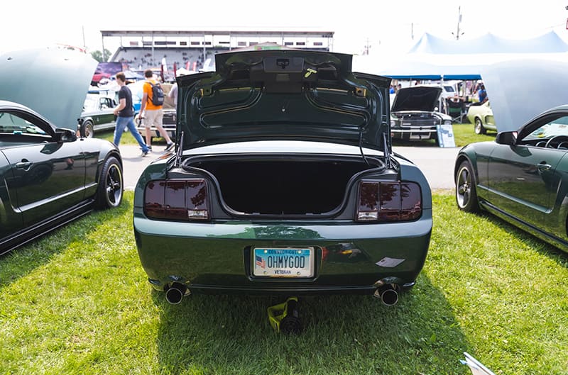 Rear view of the Mustang Bullitt parked with trunk open between other two other Mustangs