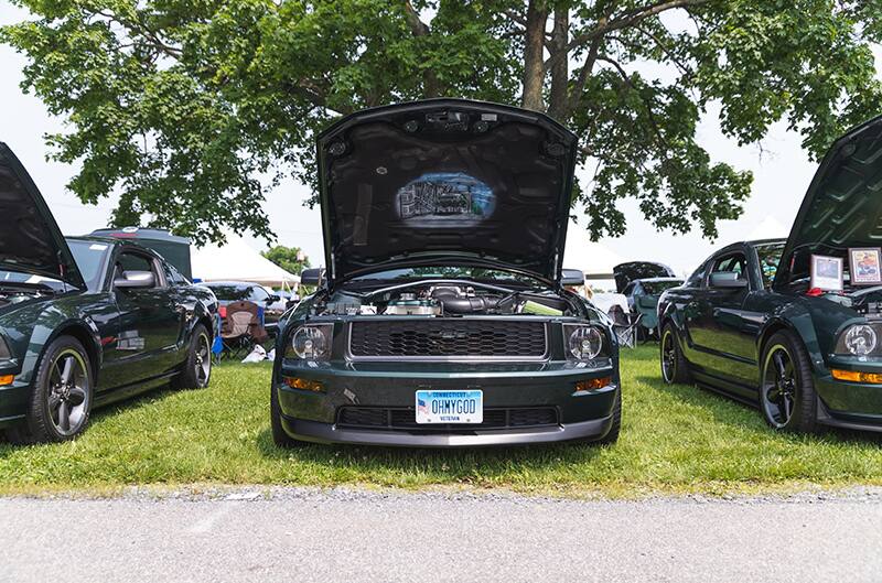 Hood of 2009 Mustang Bullitt propped open with artwork underneath on display