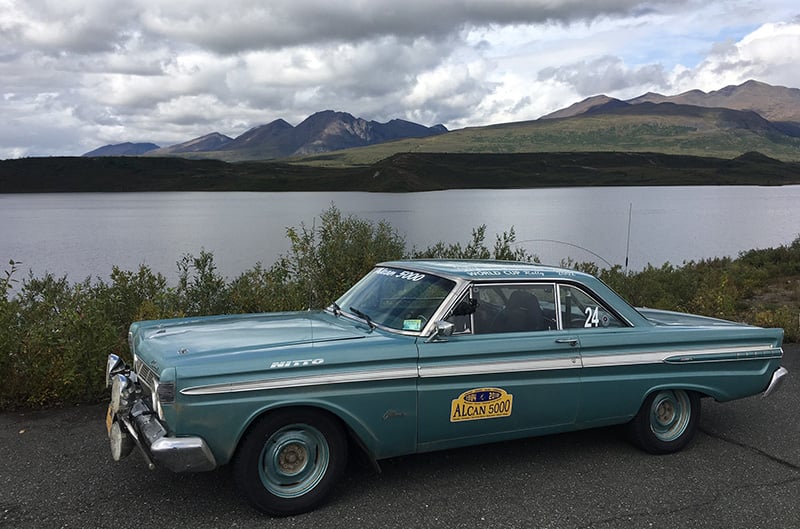 ide view of Jeffrey's 1964 Mercury Comet Caliente parked next to water and mountains