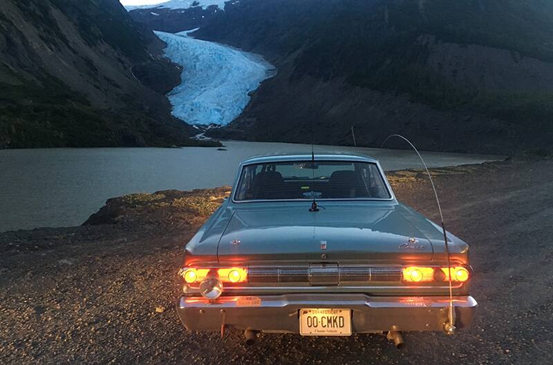 Rear view of the 1964 Mercury Comet Caliente parked in front of mountains and water