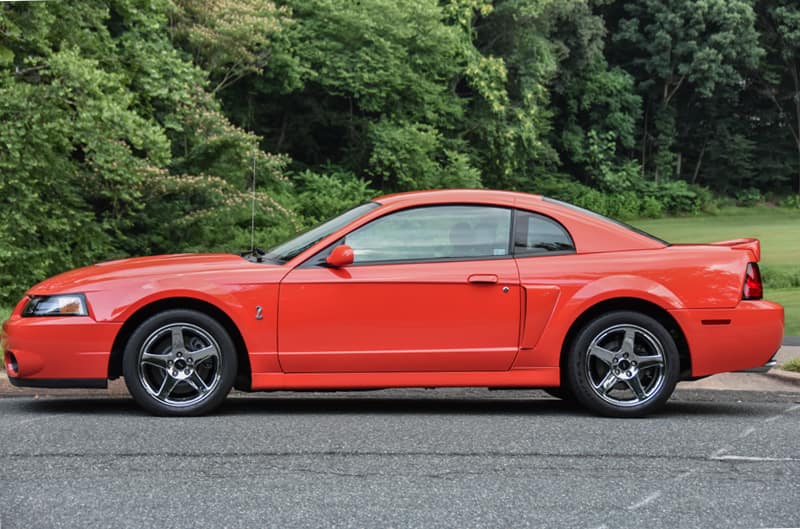 Side view of 2004 Competition Orange SVT Mustang Cobra parked on street