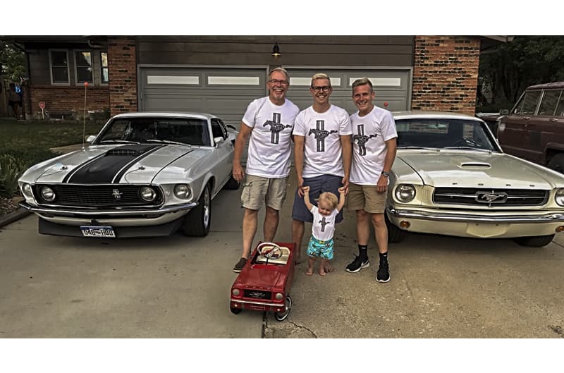 The Gillespie men posing in front of two Mustang's parked on driveway