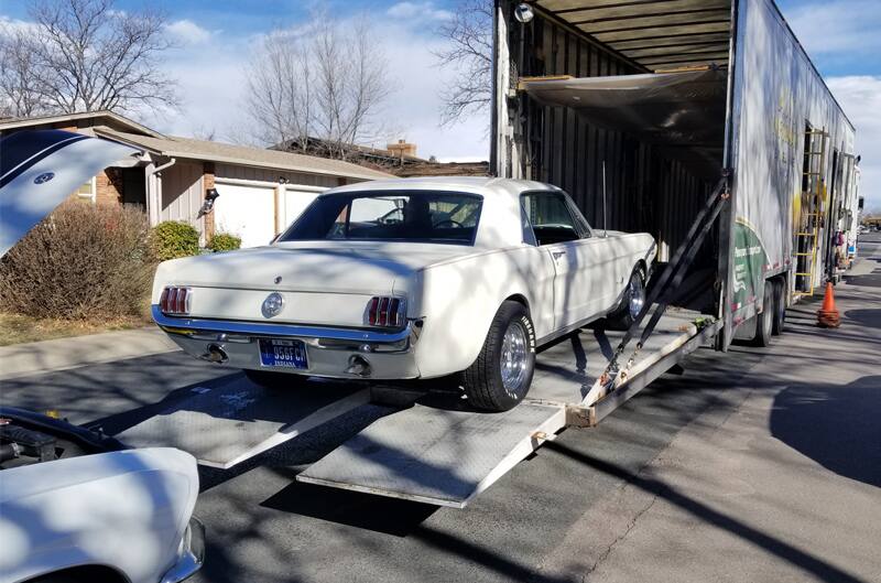 rear view of Wimbledon White 1965 Mustang GT being unloaded off of a truck