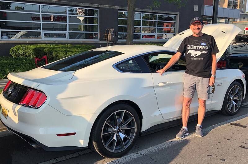 Owner Mark Russell posing outside of his Wimbledon White 2015 Mustang GT