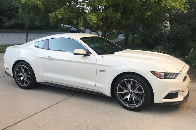Passenger side view of Wimbledon White Mustang GT parked on driveway