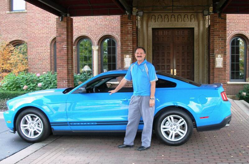 Mark Russell posed outside of his parked 2012 Grabber Blue Mustang