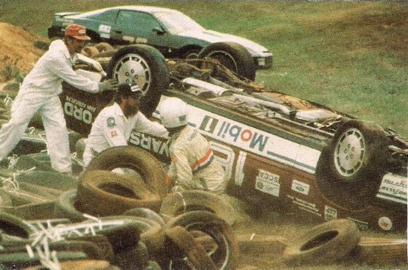 Crew members helping at race track with a flipped over race car