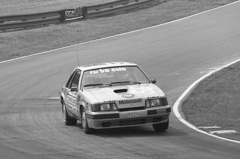 Black and white photo of Terry McKenna's silver #56 race car driving on track