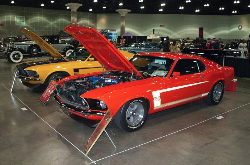 Side view of twin 1969 Boss 302 Mustangs on display with hoods propped open