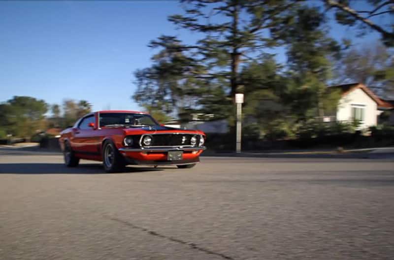 Front view of red Boss 302 Mustang in motion driving down a road