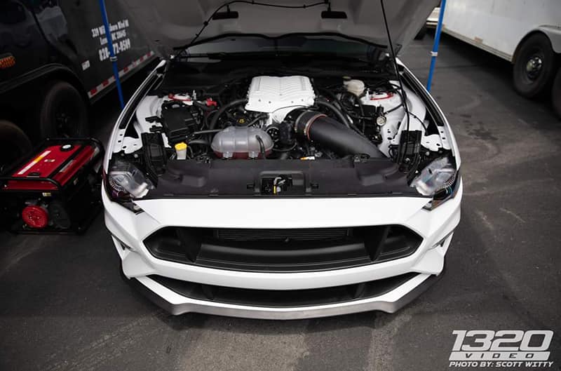 Close up of front end of white Mustang with hood open and engine exposed