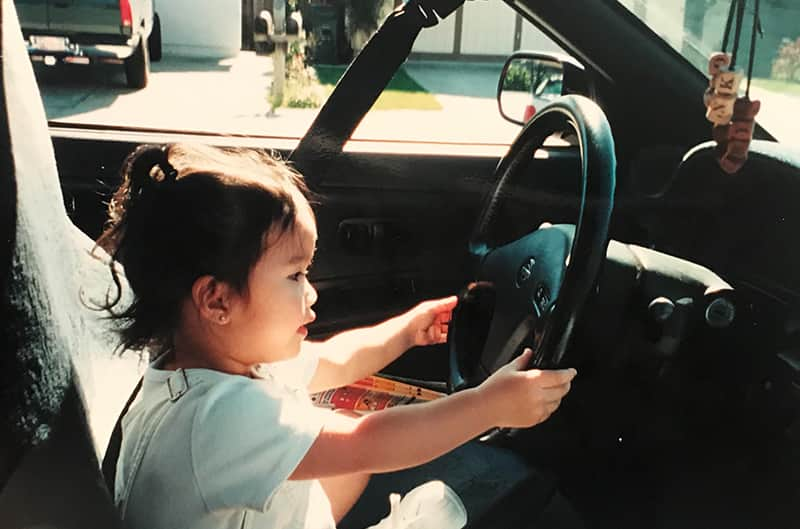 Aged photo of Gelica as a baby in the front seat of the Mustang