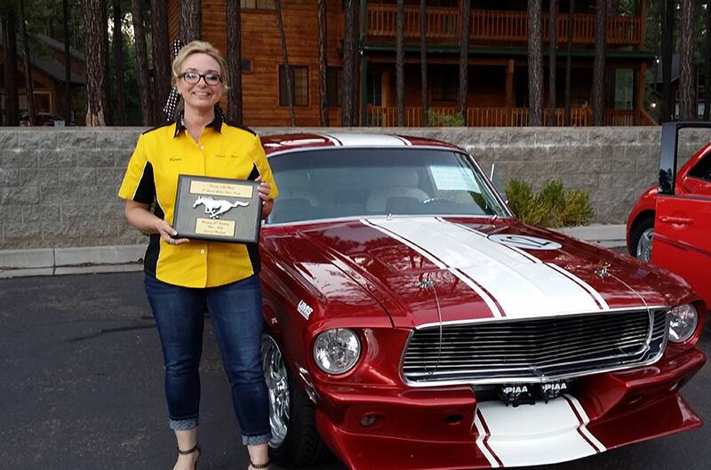 Women standing by mustang with award from car show