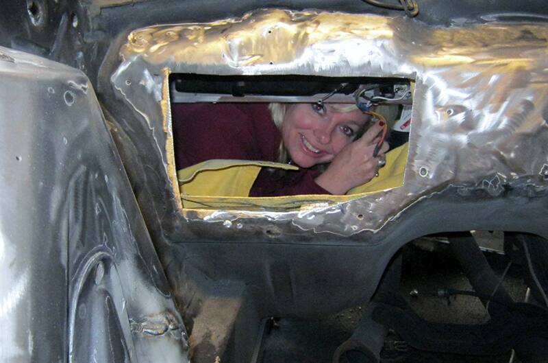 Women peering through hole in firewall of mustang from inside