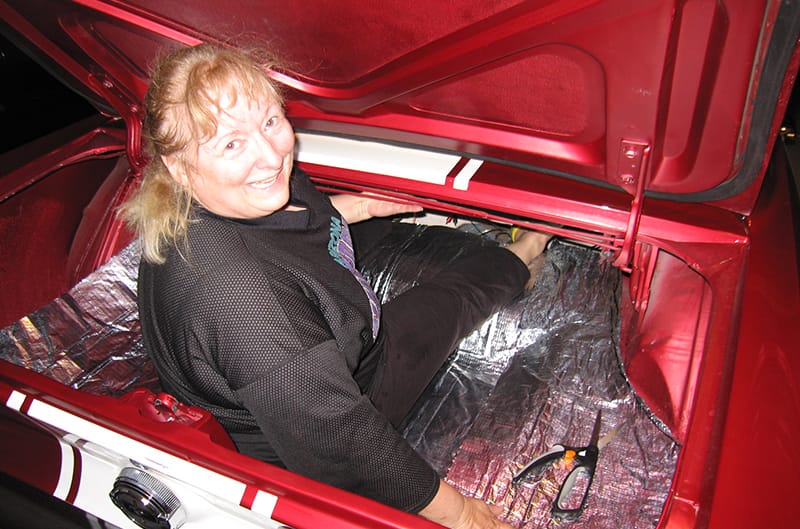 Women sitting in trunk of mustang cutting dynomat