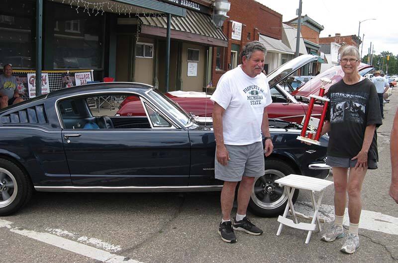 Car owners standing with Mustang and award at show