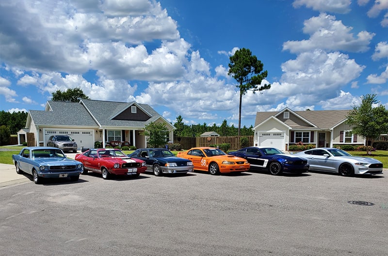 six mustangs lined up in front of home
