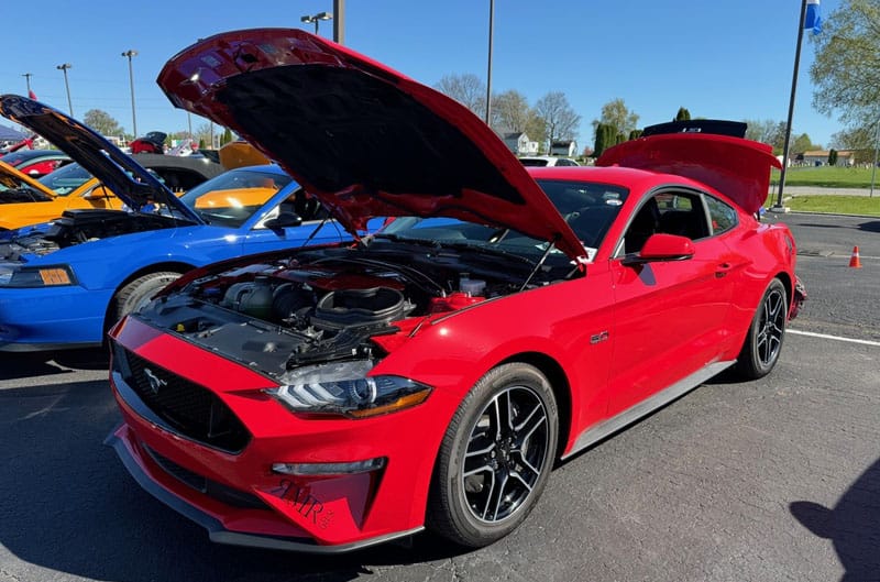 red mustang in parking lot with hood up