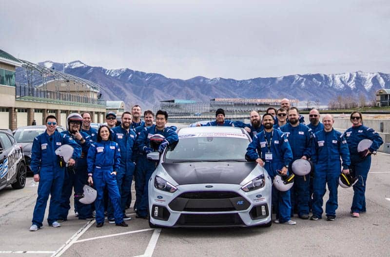 Ford Performance Racing School students surrounding a gray and black Focus RS on the track