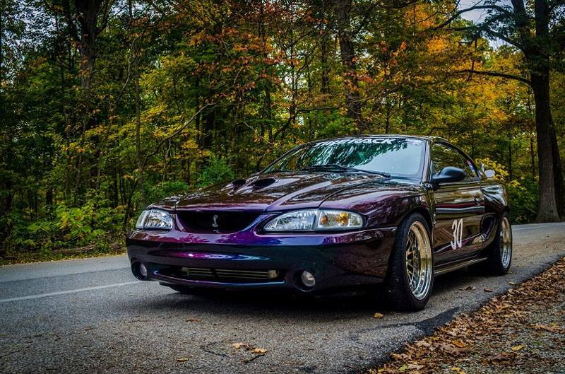 A purple Shelby Mustang driving down the road