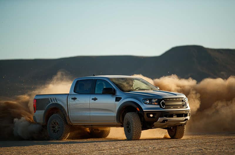 A silver Ford Ranger drifting on a dirt road