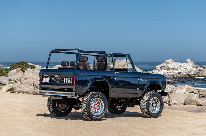 A rear side view of a custom blue Ford Bronco