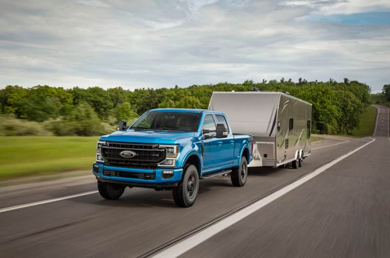 Front of blue F250 pulling a trailer on the road