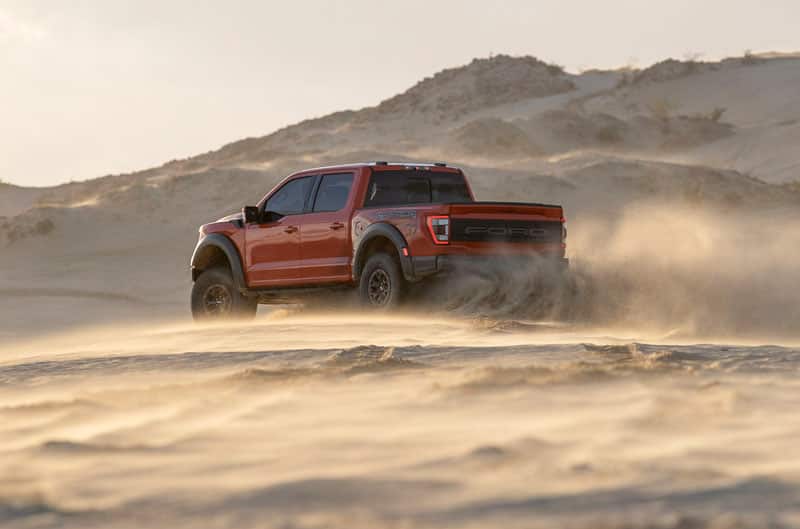 Rear profile of red Raptor drifting in the dirt