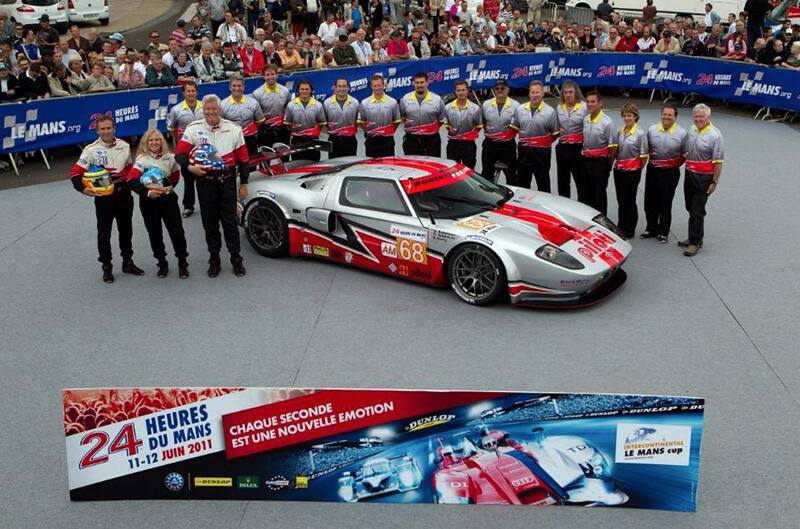 Team standing around red and silver ford GT