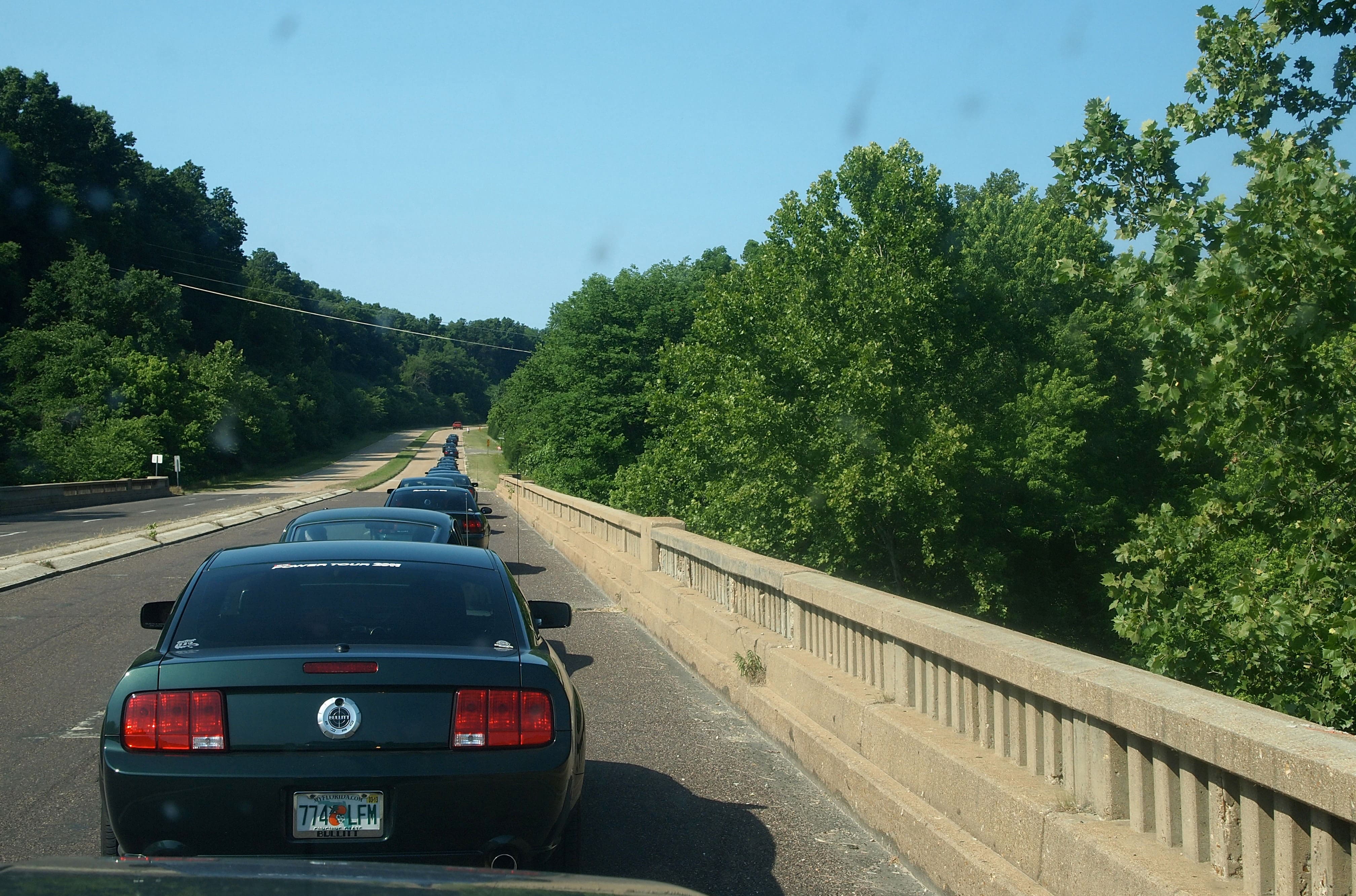 Several Bullitt Mustangs in highland green color are pictured on the road