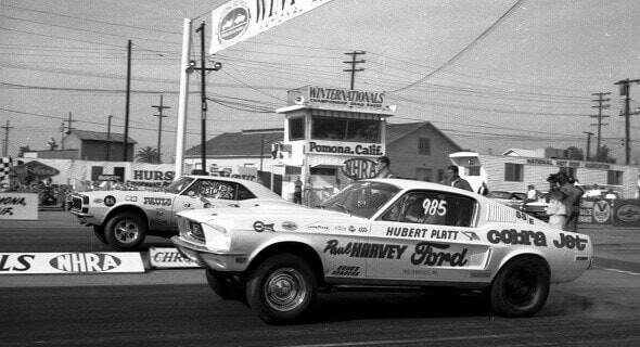 A drag race involving two Ford Mustang Cobras