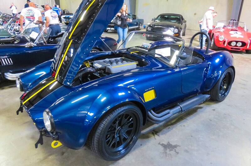 A front side view of a classic blue vehicle on display with the hood up