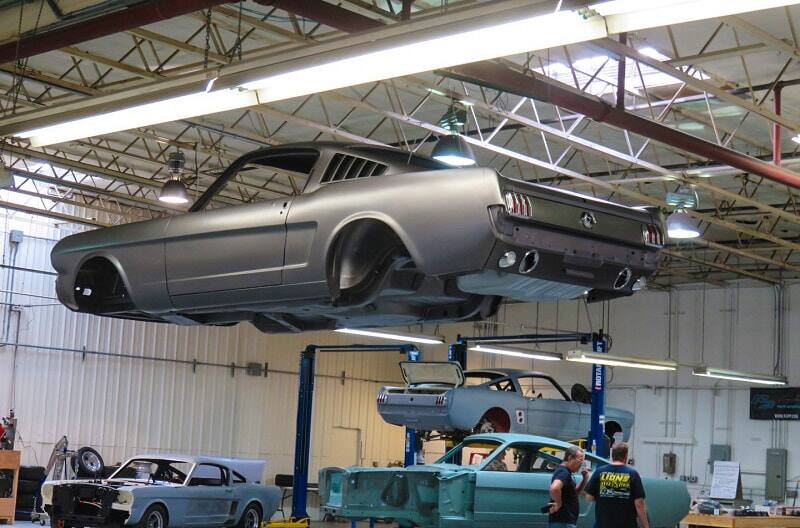 A silver Mustang lifted in the air at a car shop