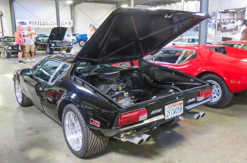 A rear side view of a black vehicle on display with the trunk open