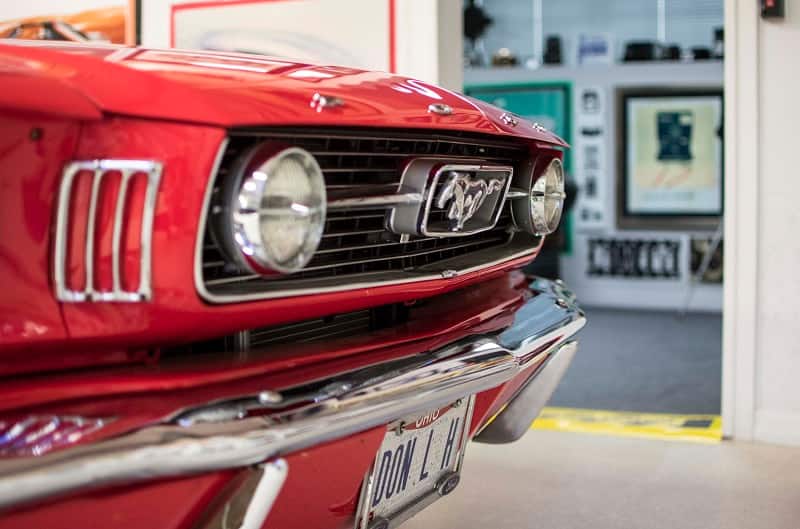 A front side view of the front end of a classic red Mustang