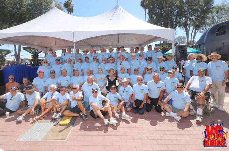 A group of people posing for a photo at the car show