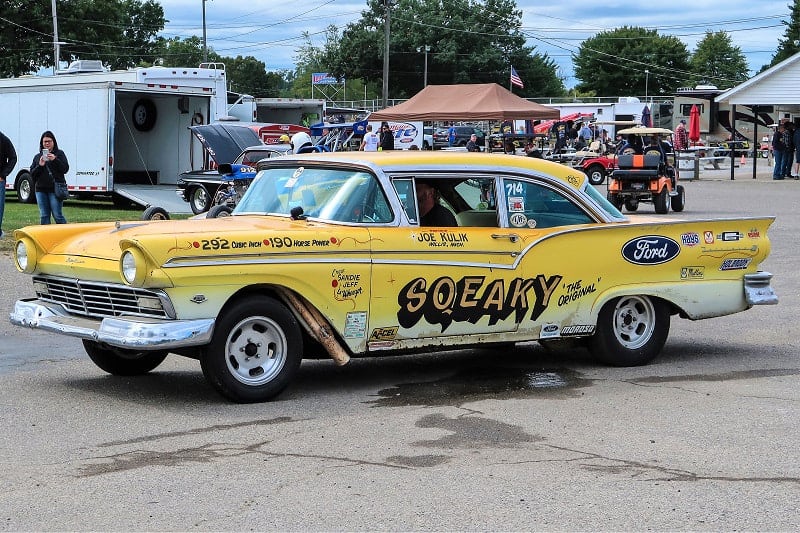 A side view of a classic yellow vehicle on display